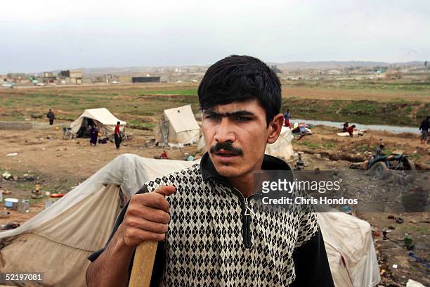 Worker shovels dirt for house while tents for Kurds waiting for homes sit in the background February 13, 2005 in Kirkuk, Iraq. Home building is...