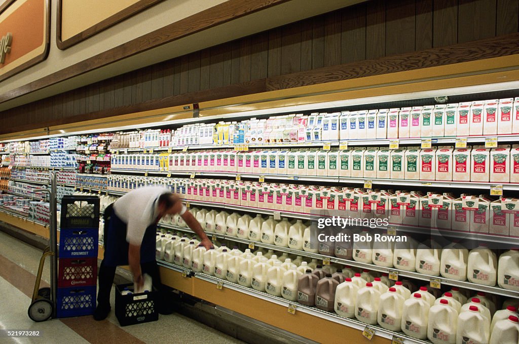 Grocery Store Clerk Stocking Shelves with Milk