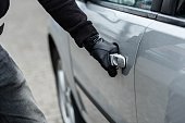 car thief hand pulling the handle of a car