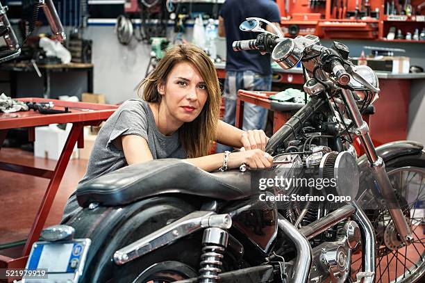 portrait of female mechanic in motorcycle workshop - bike mechanic stockfoto's en -beelden