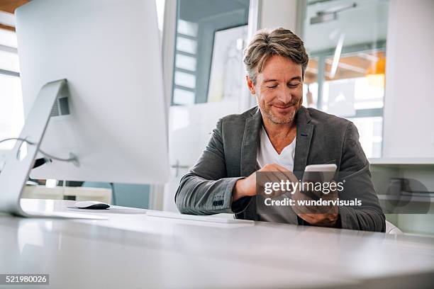 líder de equipe enviando mensagem de celular com membros de equipe e sorrindo alegremente - texting - fotografias e filmes do acervo