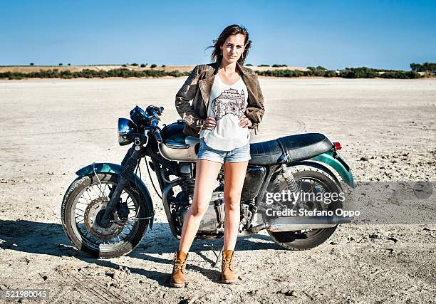 portrait of female motorcyclist on arid plain, cagliari, sardinia, italy - arid stock pictures, royalty-free photos & images