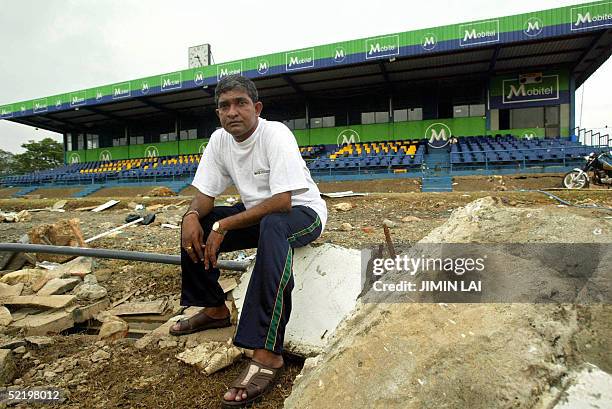 Sri Lankan cricket figure Jayananda Warnaweera sits on the rubble strewn all over the cricket pitch at the Galle international cricket stadium in the...