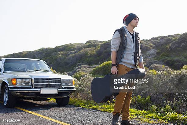 young man on roadside with guitar case, cape town, western cape, south africa - guitar case fotografías e imágenes de stock