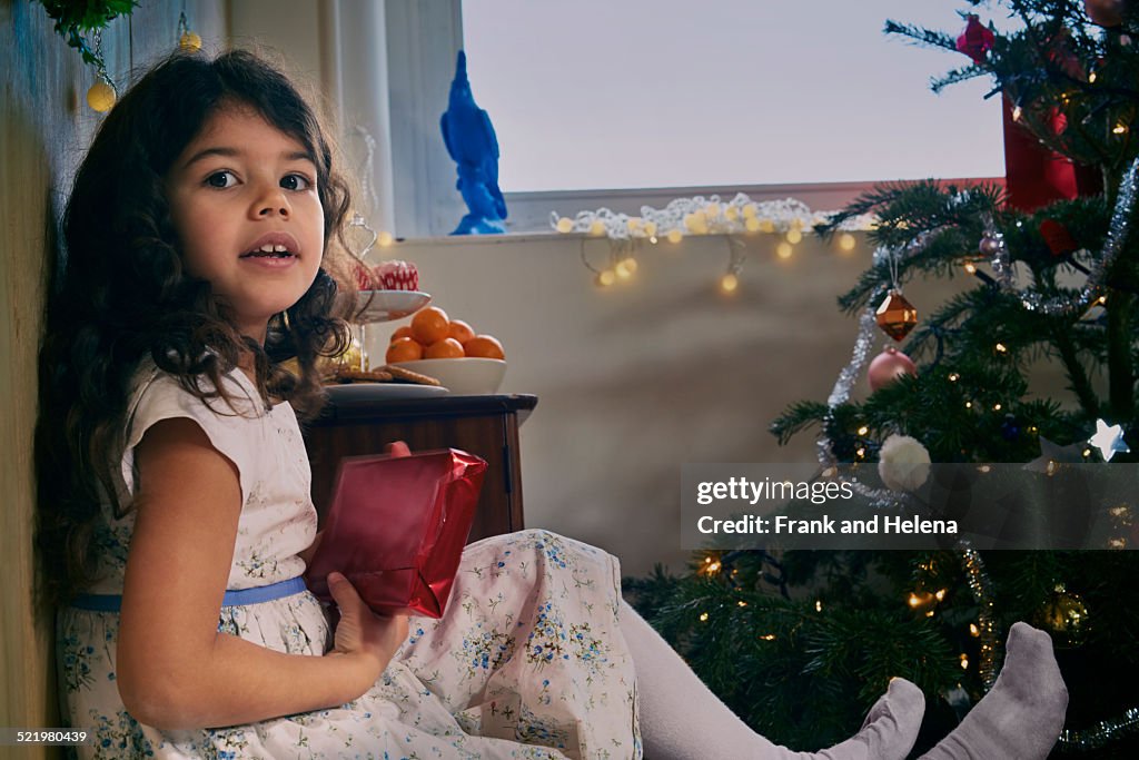 Portrait of girl sitting on floor with christmas present