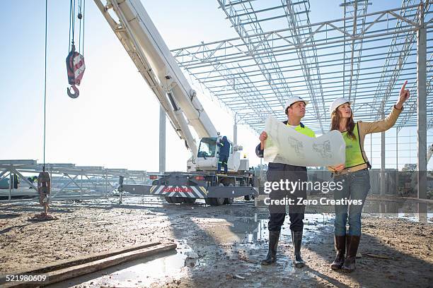 site manager and architect checking blueprint on construction site - architekt helm plan stock pictures, royalty-free photos & images