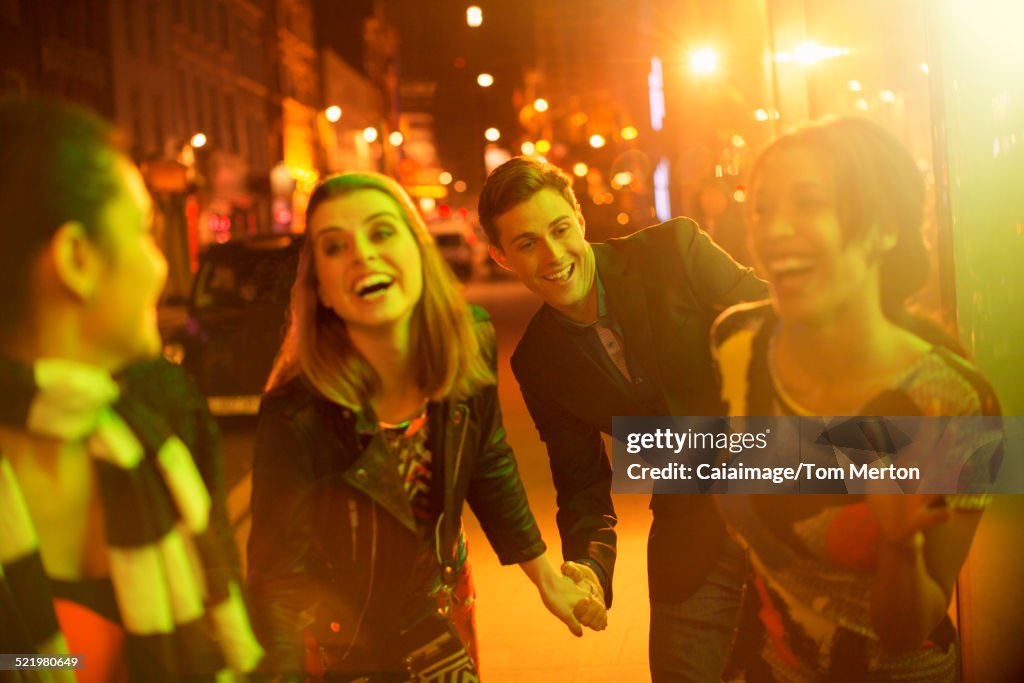 Friends walking down city street together at night