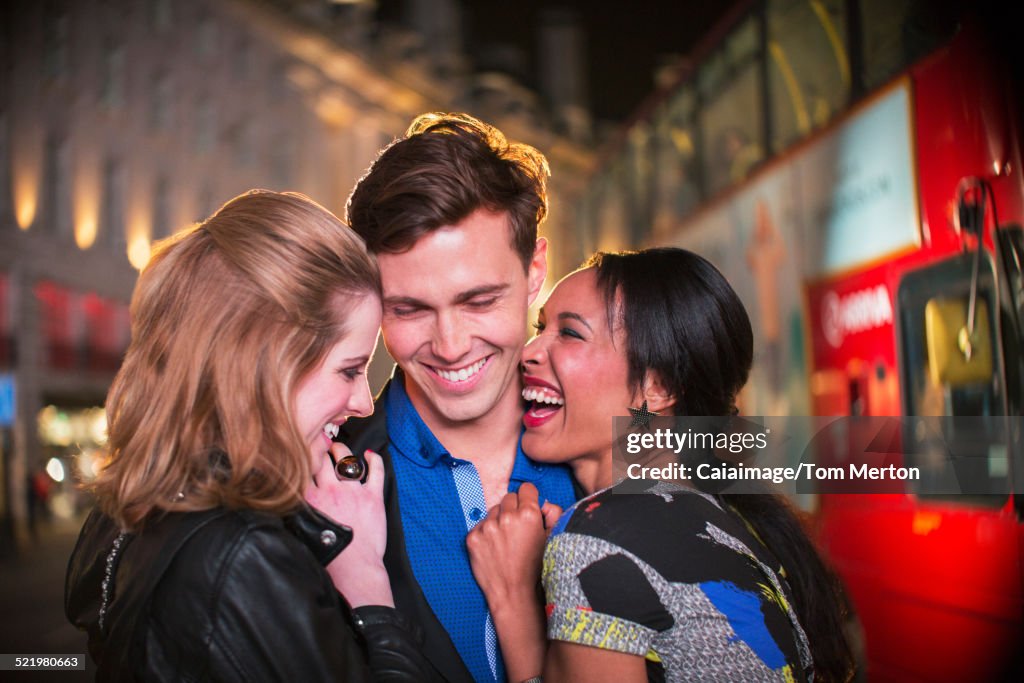 Friends hugging on city street at night