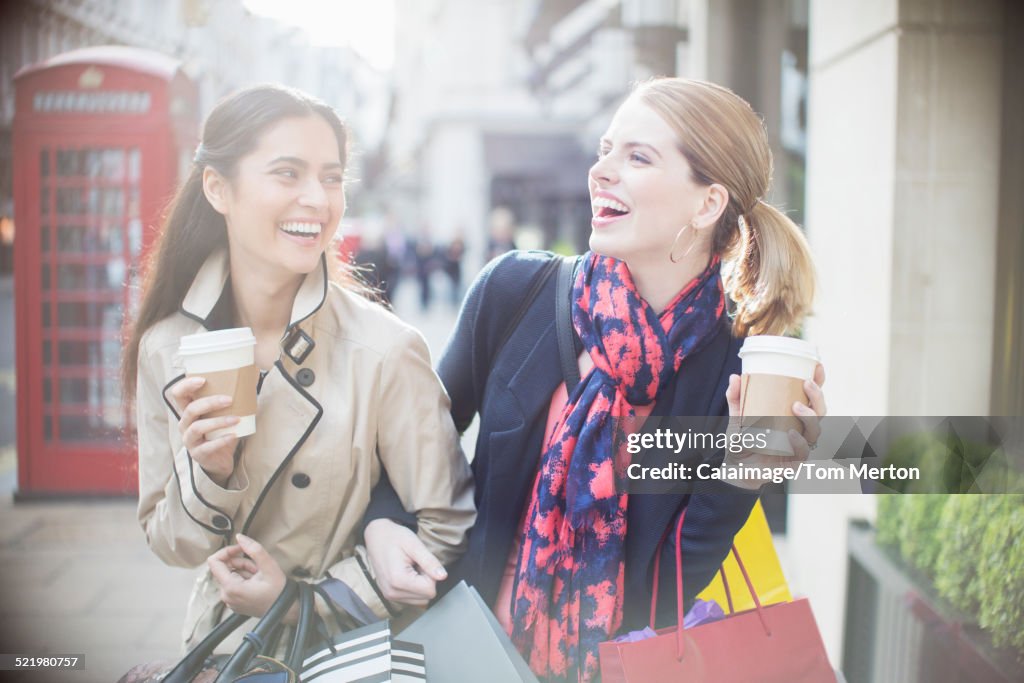 Women drinking coffee together on city street