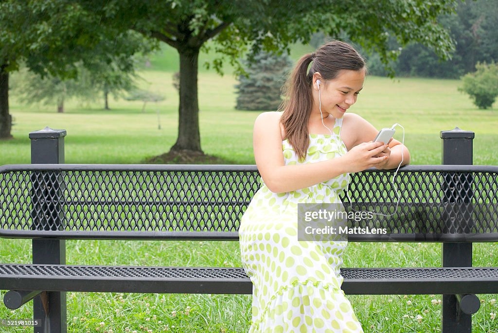 Girl sitting on bench listening to music