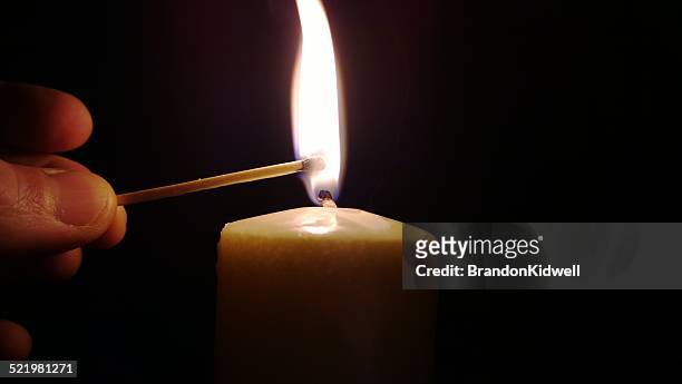 man lighting a candle with a match - candela attrezzatura per illuminazione foto e immagini stock