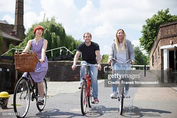 friends riding bike along canal, east london, uk - east london fotografías e imágenes de stock