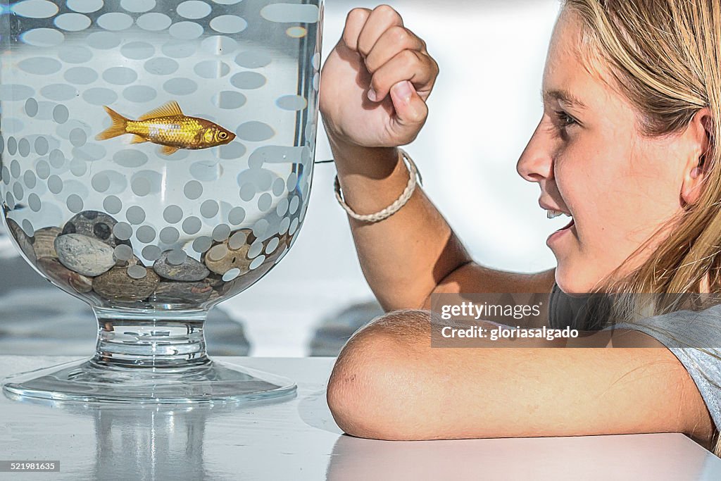 Girl looking at goldfish in a bowl