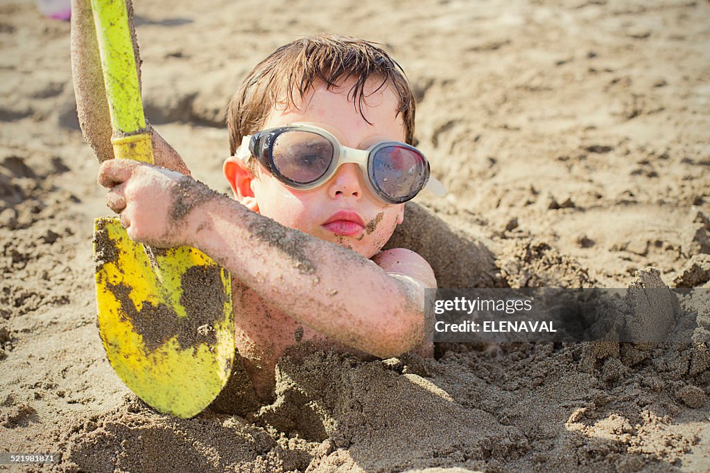 Portrait of a Boy buried in sand on beach