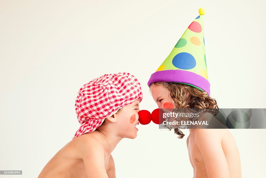 Boy and girl dressed in clown outfits messing about