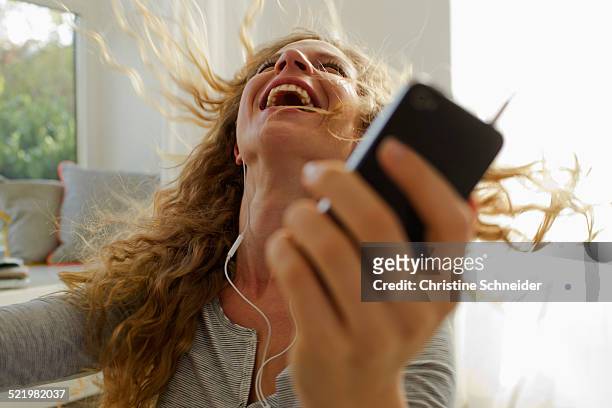 woman dancing to music on smartphone - joy stock-fotos und bilder