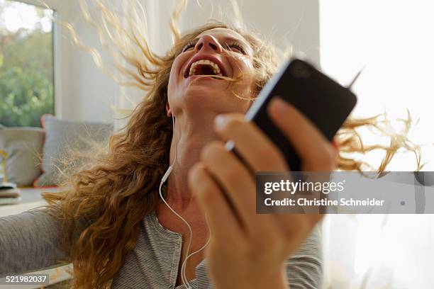 woman dancing to music on smartphone - action laptop fotografías e imágenes de stock