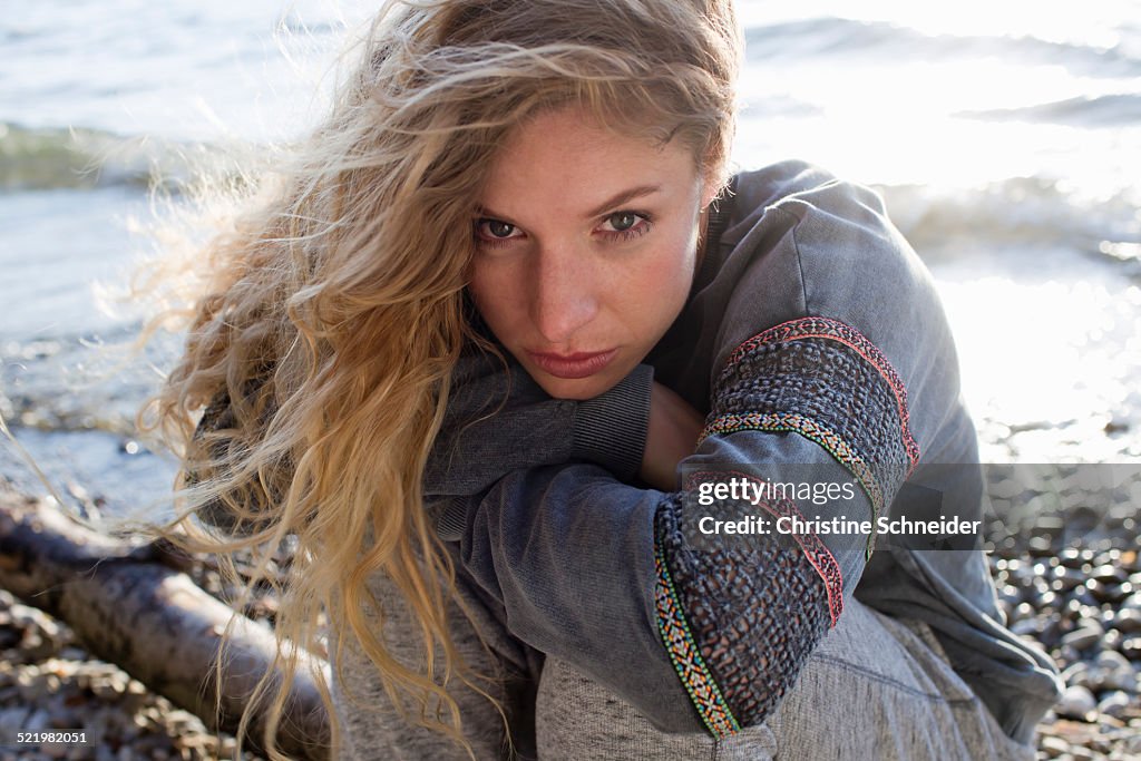 Woman sitting on windy beach