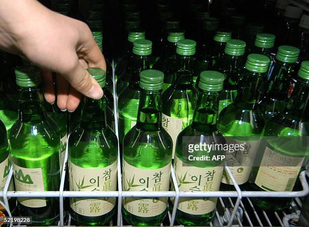 South Korean shopper holds a Jinro liquor bottle at a convenience store in Seoul, 15 February 2005. South Korean beverage companies and foreign firms...