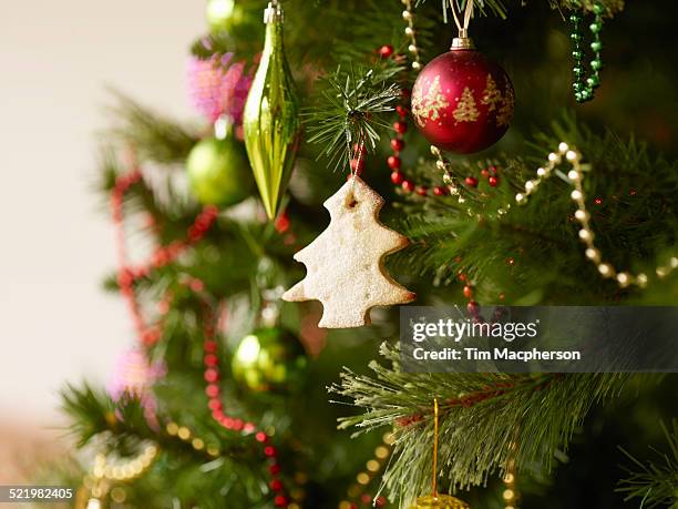 close up of christmas tree with baubles and christmas biscuits - food decoration stock-fotos und bilder