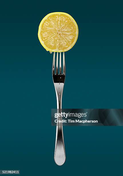 still life of fresh slice of lemon on fork - halstock stock-fotos und bilder