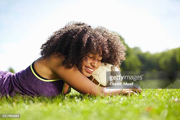 young woman taking a break in park leaning on football - couch potato expressão em inglês - fotografias e filmes do acervo