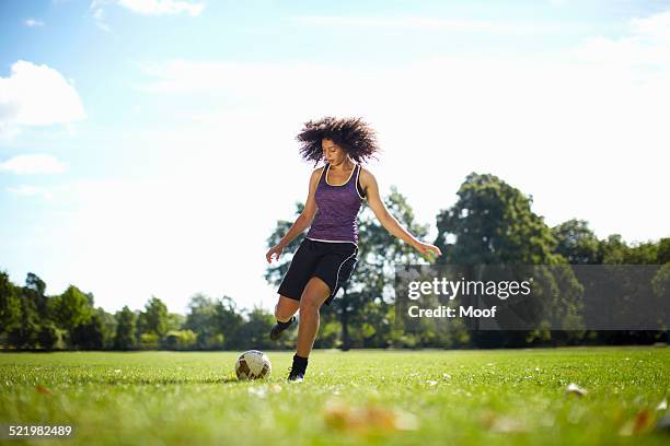 young woman kicking soccer ball in park - england football day stock pictures, royalty-free photos & images