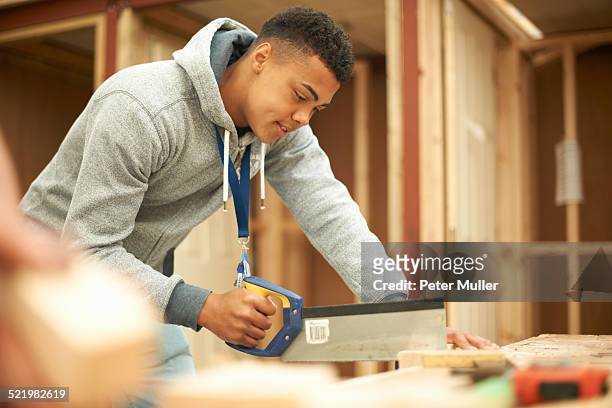 male college student using saw in woodworking workshop - sawing stock pictures, royalty-free photos & images