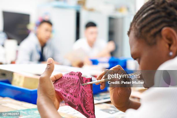 male student painting on swatch of fabric in textile class - cornrows stock pictures, royalty-free photos & images