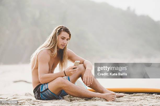 australian surfer using smartphone, bacocho, puerto escondido, mexico - long hair man stock pictures, royalty-free photos & images
