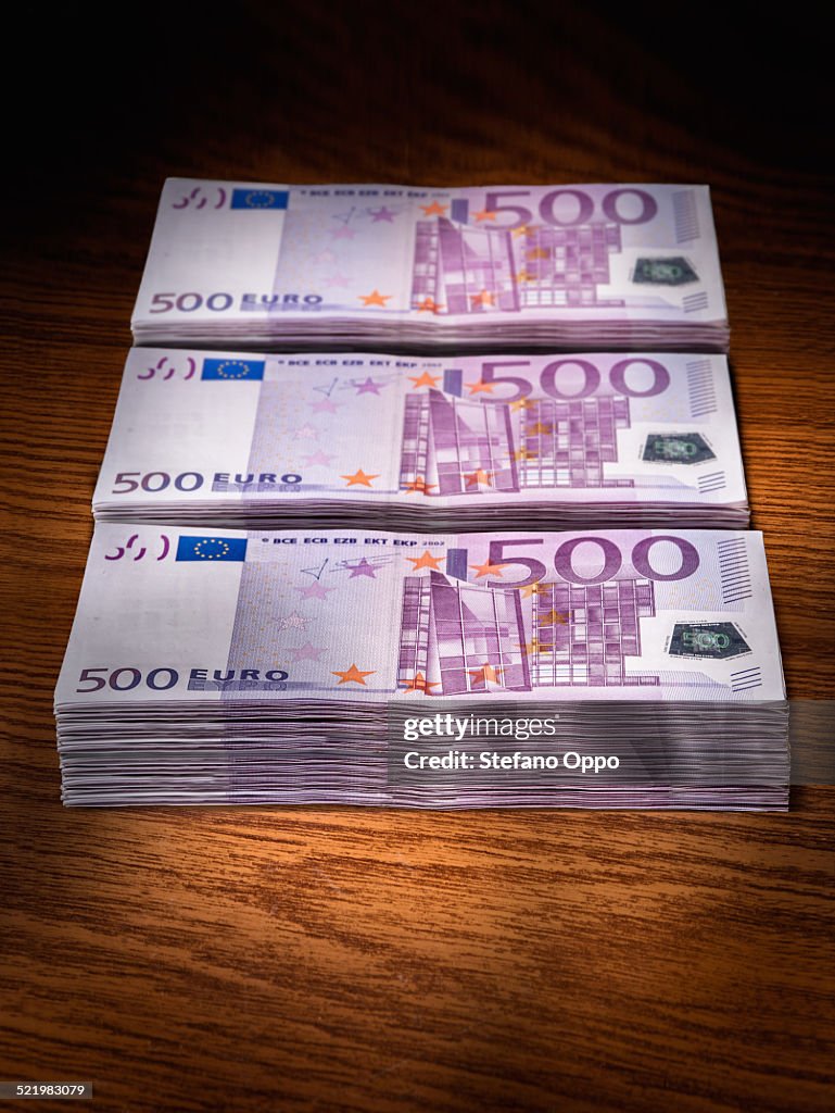 Three stacks of 500 euro bills on office desk