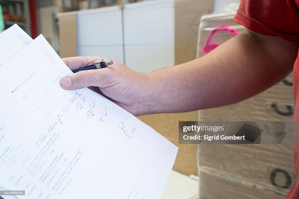 Hand of male warehouse worker collecting order for hardware store