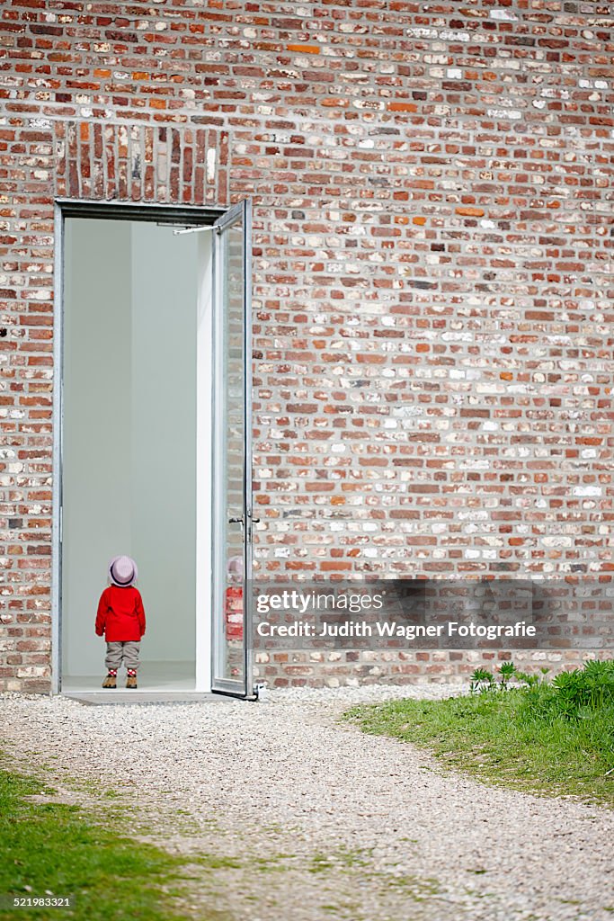 Young girl standing in doorway in brick wall