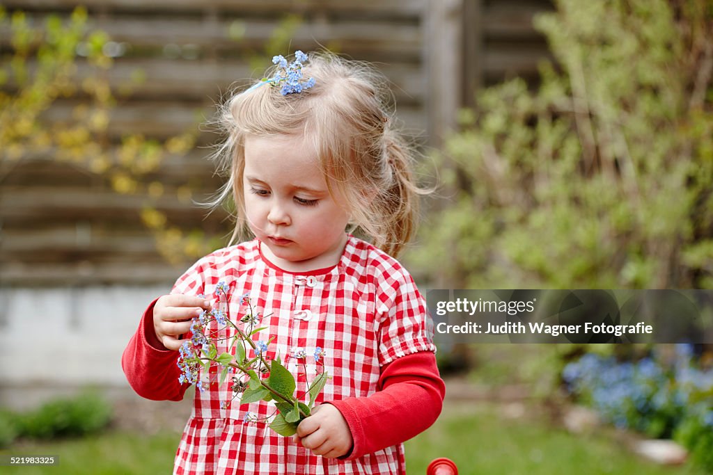 Young girl wearing gingham dress holding flowers