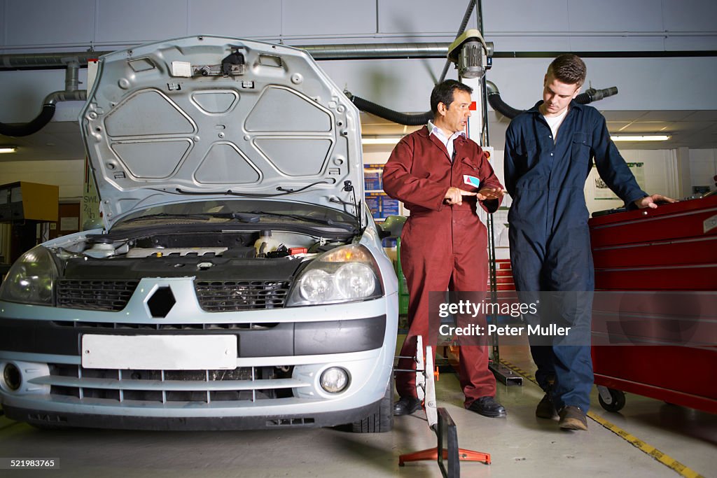 Lecturer explaining to male student in college garage