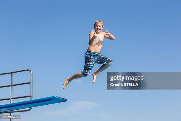 boy, 10 years, jumping from a three-meter board making a thumbs up gesture - diving platform stock pictures, royalty-free photos & images