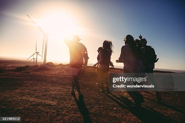 friends walking towards vintage car at sunset in wind park - wind turbine california stock pictures, royalty-free photos & images