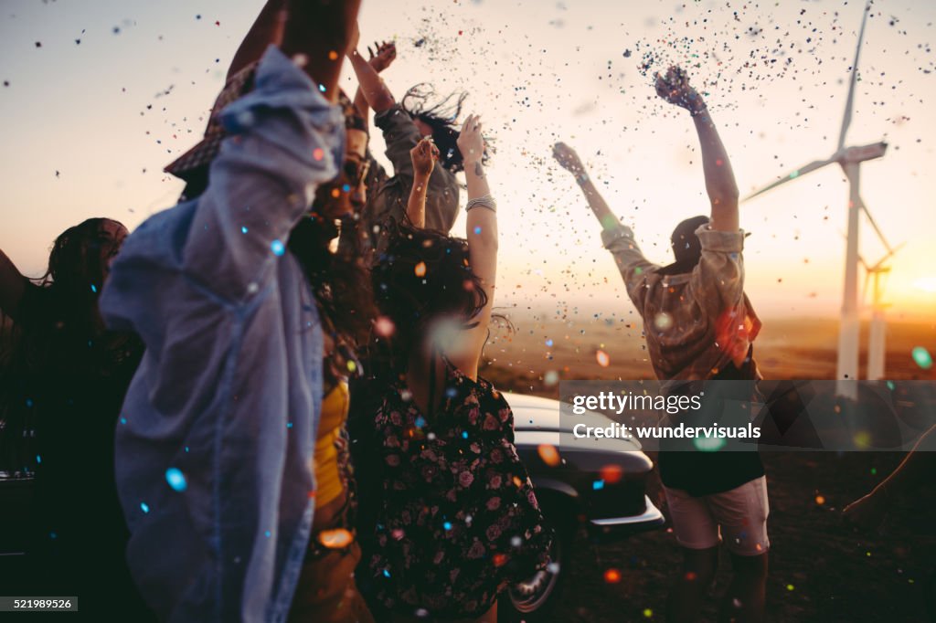 Teenagers celebrating with colourful confetti on summer road tri