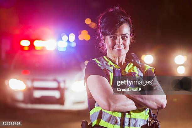 female police officer at night, lights on patrol car - traffic cop stock pictures, royalty-free photos & images