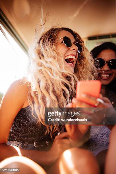 hipster girl looking at smart phone with road trip friend - teenage girls stock pictures, royalty-free photos & images