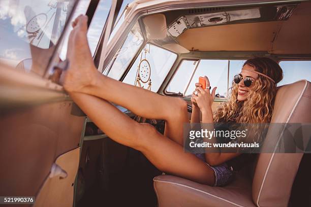 road trip boho girl sitting in vintage van with smartphone - take a vintage summer road trip stock pictures, royalty-free photos & images
