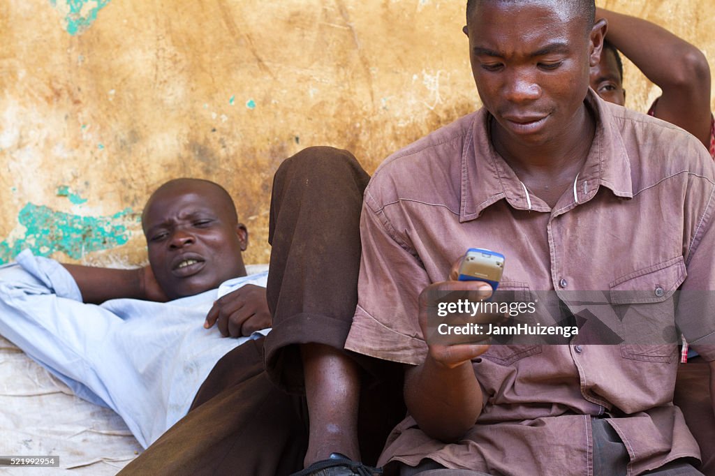 Mwanza, Tanzania: Men Relaxing, One with Cell Phone