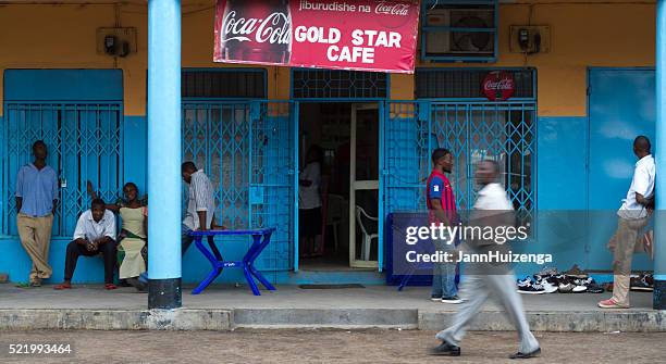 mwanza, tanzania: locals relax outside a colorful cafe - pepsi centre stock pictures, royalty-free photos & images