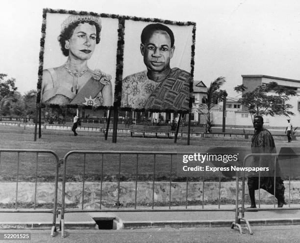 Man wearing Kente cloth walks past a portrait of Ghanaian president Kwame Nkrumah and an unflattering portrait of Queen Elizabeth II, erected for the...