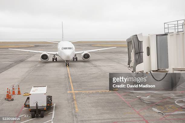 airliner and passenger gangway on runway, auckland, north island, new zealand - airplane gangway stock pictures, royalty-free photos & images