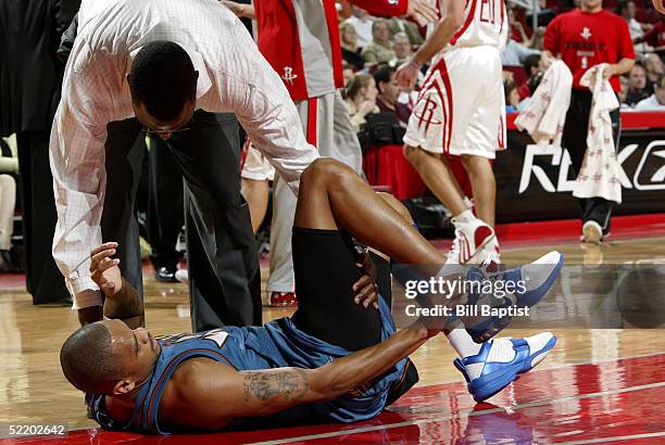 Juan Dixon of the Washington Wizards is tended to by Keith Jones, trainer for the Houston Rockets, after suffering a right ankle sprain during the...