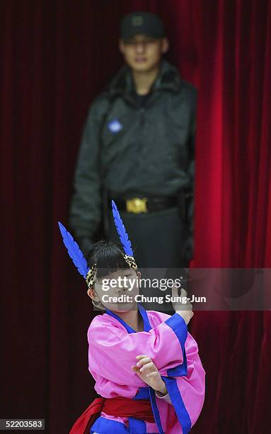 South Korean soldier stands guards while a student of Taesungdong Elementary School performs a traditional dance during the graduation ceremony for...