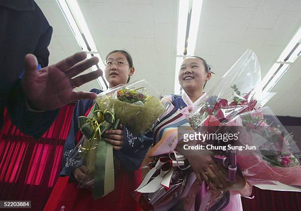 Jeon Hee-Ryung and Lee Na-Young , graduates of Taesungdong Elementary School, hold flowers after their graduation ceremony on February 16, 2005 in...