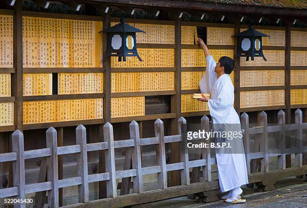 priest adds donor tablets to wall - yasaka shrine stock pictures, royalty-free photos & images