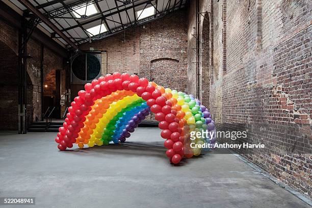 empty warehouse with rainbow made of balloons - インスタレーション ストックフォトと画像